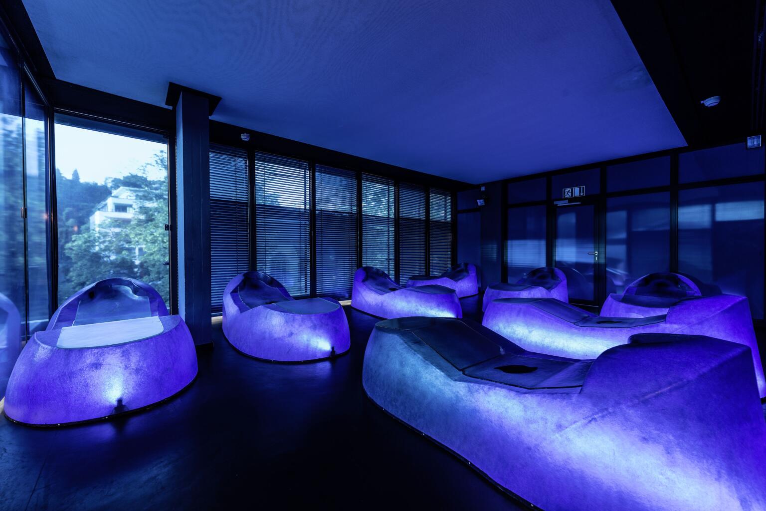 Blue Space Ruheraum der Caracalla Therme Baden-Baden mit futuristisch beleuchteten Liegen in blau-violettem Licht.